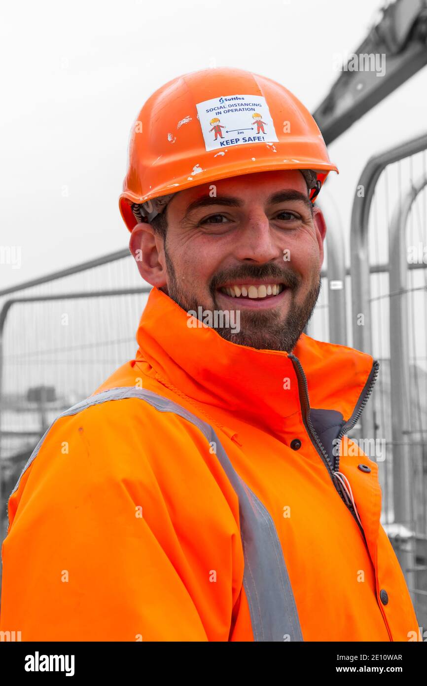 Sicurezza marshall indossare giacca alta viz arancione e casco di sicurezza con distanza sociale in funzione 2m a parte tenere al sicuro a Bournemouth, Dorset UK Foto Stock