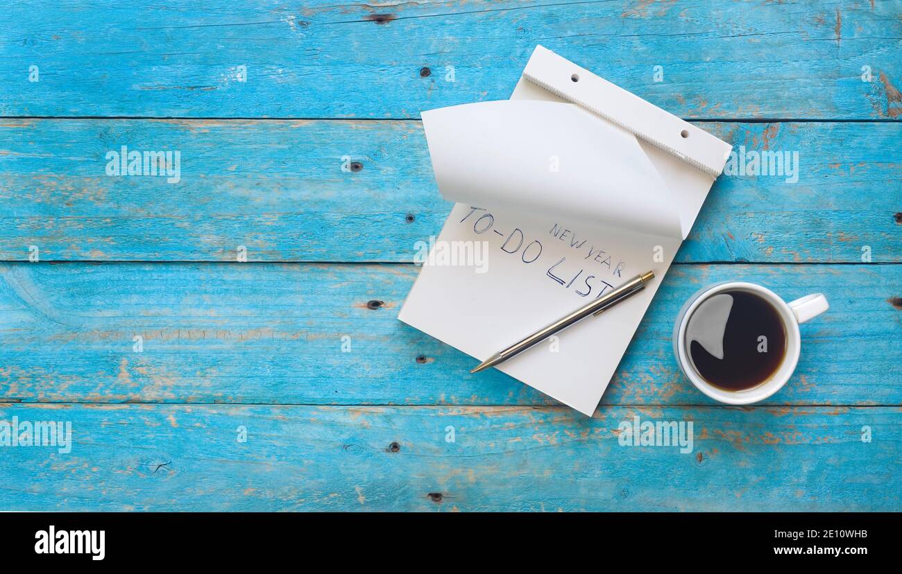 Le risoluzioni del nuovo anno si simulano con il pad di scrittura, il testo e la tazza di caffè, la disposizione piatta, lo spazio libero di copia Foto Stock