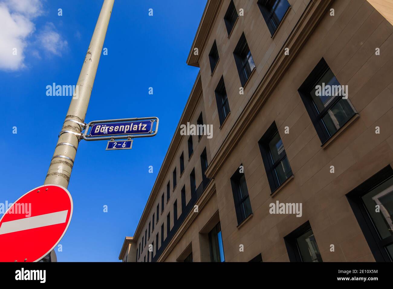 Cartello stradale con indicazione per la Borsa di Francoforte. Edificio d'affari con scritte e facciata marrone. Ufficio che costruisce cielo blu con nuvola in s. Foto Stock