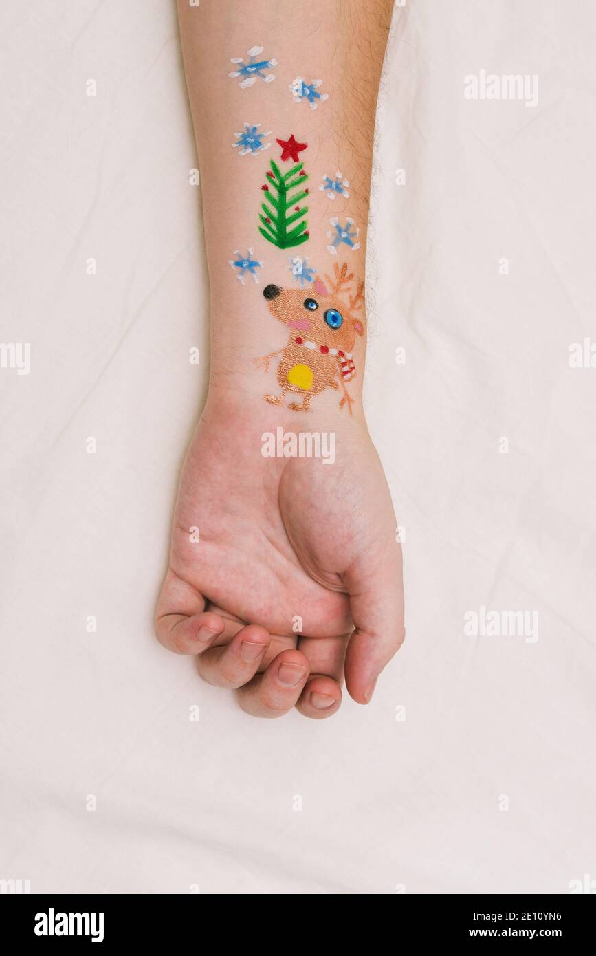 Disegno di Natale sulla mano di un uomo. Albero di Natale, cervi e fiocchi di neve. Sfondo festivo. Mano su un foglio bianco. Foto Stock