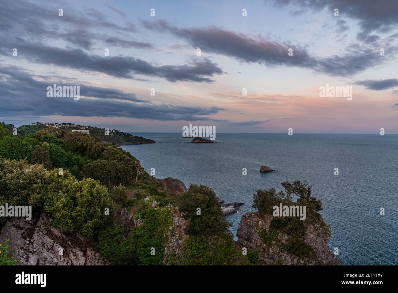 Luce serale su Daddyhole Cove, con vista sulle scogliere, il mare e Thatcher Rock a Torquay, Torbay, Inghilterra, Regno Unito Foto Stock