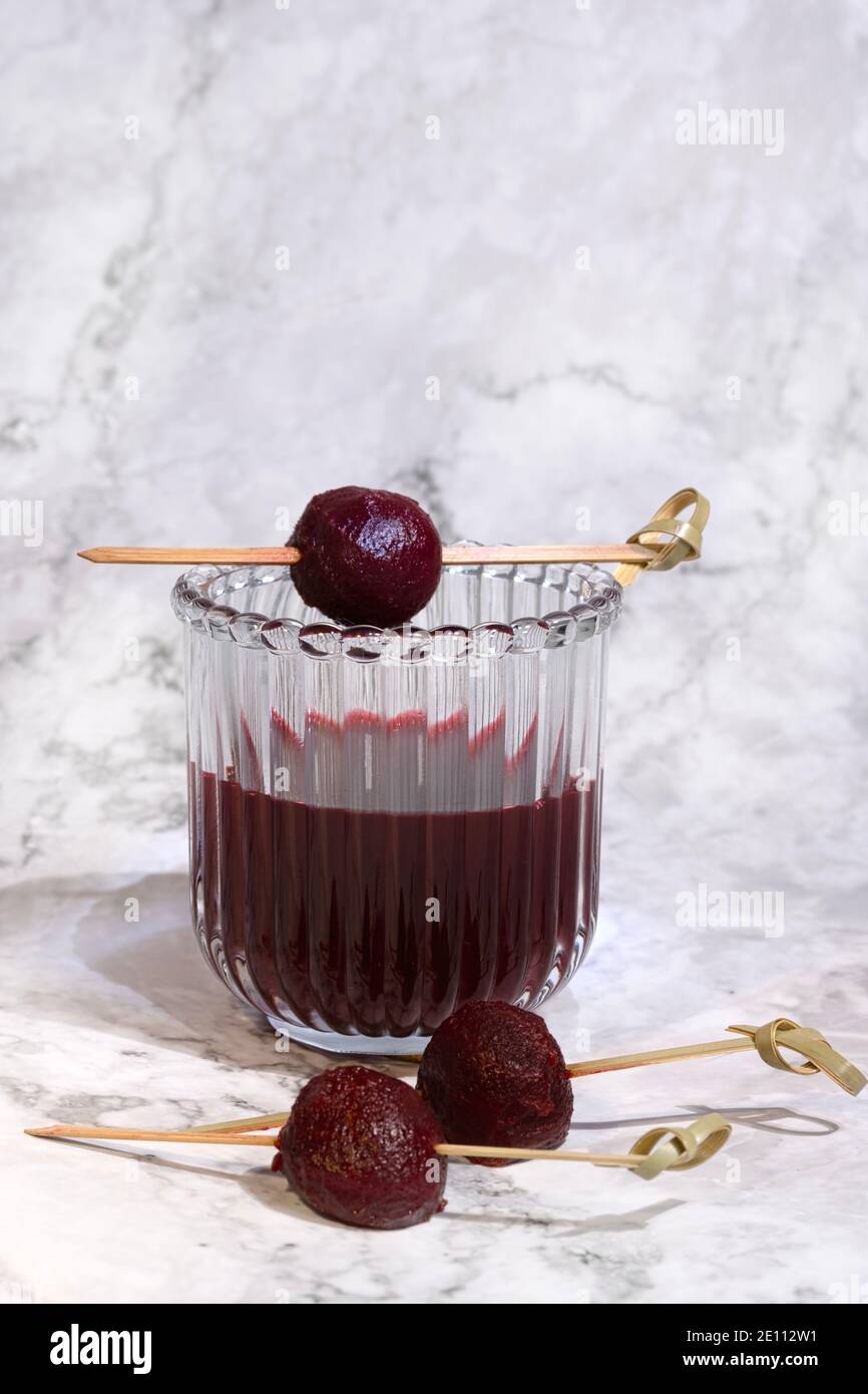 Succo di barbabietola rosso fatto in casa splendidamente sistemato in tre bicchieri su un tavolo di marmo, vista dall'alto, ritratto, ombra dura Foto Stock