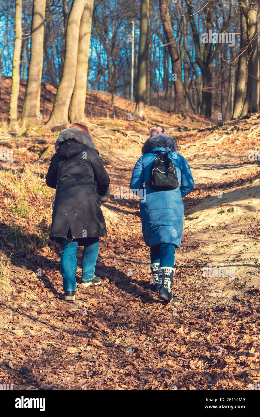 Due ragazze vanno in salita. Donna trekking attraverso boschi verdi vegetazione, in salita. Turismo e concetto di viaggio Foto Stock