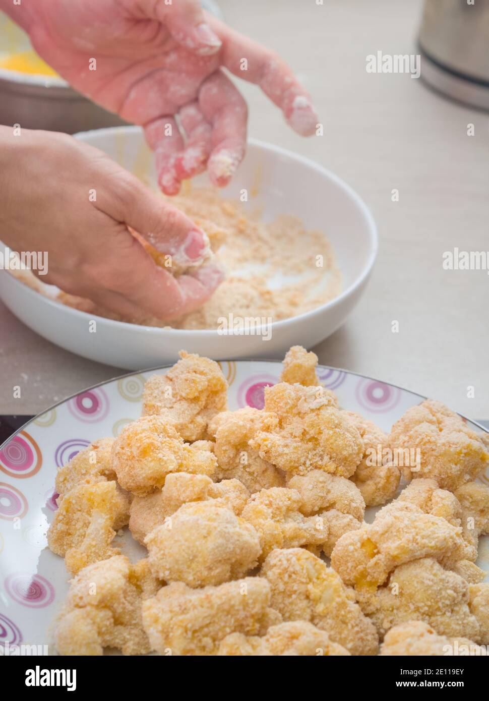 Mani che ricopra il cavolfiore in Breadcrumbs in cucina Foto Stock