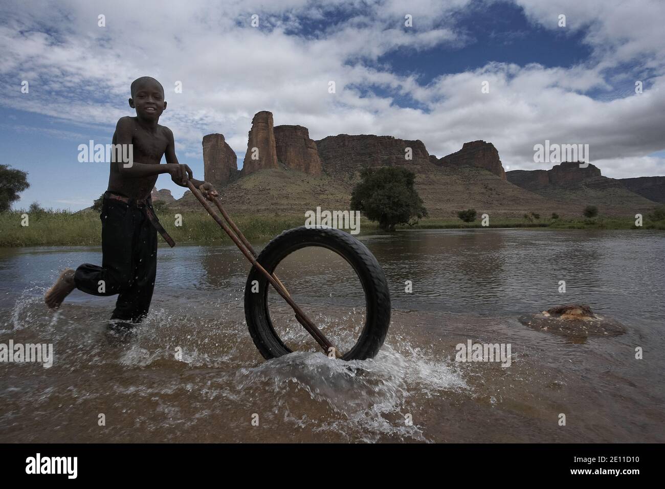 Bambino africano che gioca con una ruota, Mali, Africa occidentale. Foto Stock