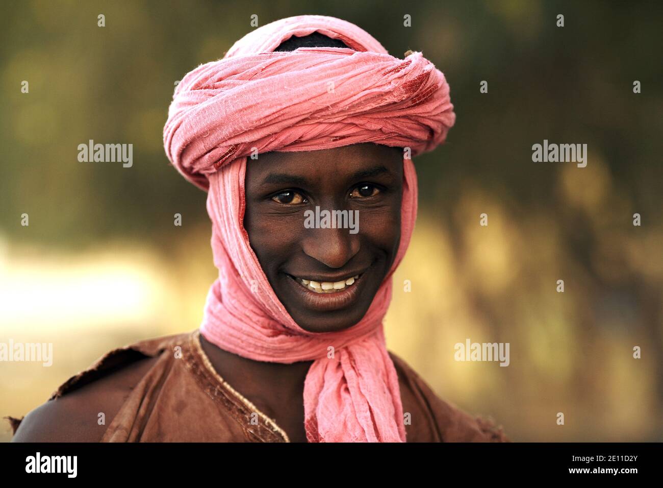 Un giovane con un Turban rosa sta dando un grande sorriso a Mali, Africa occidentale. Foto Stock