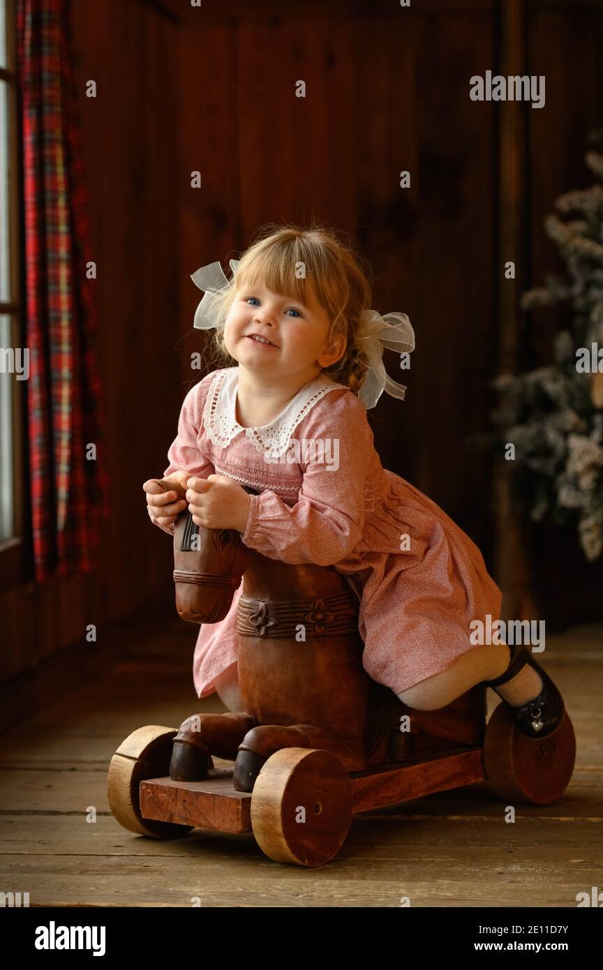 Bambina carina bionda in piedi alla testata del letto di ferro Foto Stock