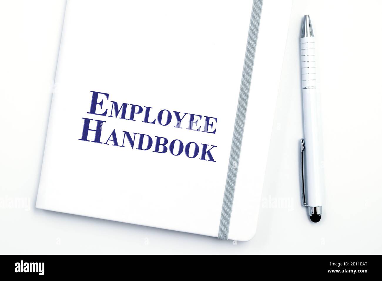 White Employee Handbook o manuale con penna bianca sulla superficie bianca del tavolo - la politica di gestione del personale, spiega gli obiettivi aziendali, i risultati, definisce la Leade Foto Stock