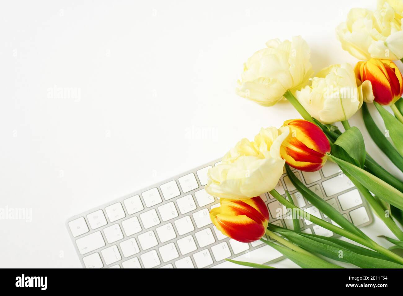 Piatto mentire San Valentino sfondo con tastiera per computer e bouquet di tulipani. Vista dall'alto. Spazio vuoto per la copia Foto Stock