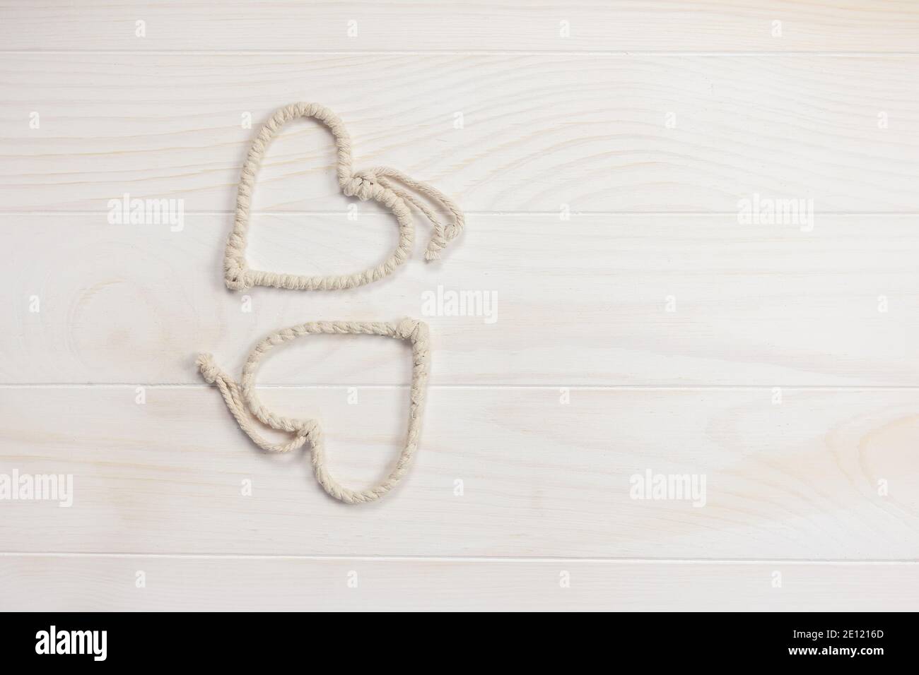 Composizione Flatlay con bellissimi cuori di corda carino su uno sfondo di legno bianco. San Valentino. Spazio di copia. Foto Stock