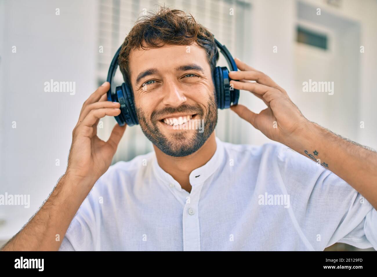 Bell'uomo con la barba che indossa le cuffie e ti piace ascoltare musica  all'aperto Foto stock - Alamy