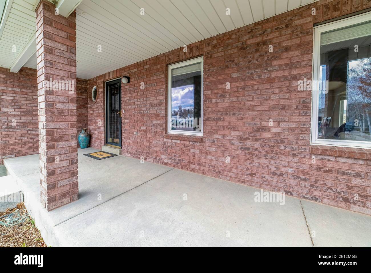 Ampio e aperto avvolge intorno portico di cemento di casa con parete esterna in mattoni Foto Stock