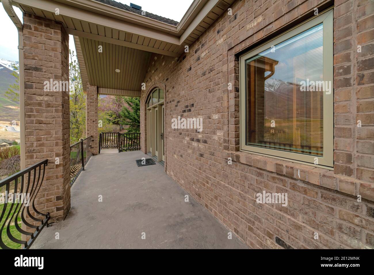 Balcone della casa con muro di mattoni e porta di vetro sotto finestra  sullo specchio di poppa ad arco Foto stock - Alamy