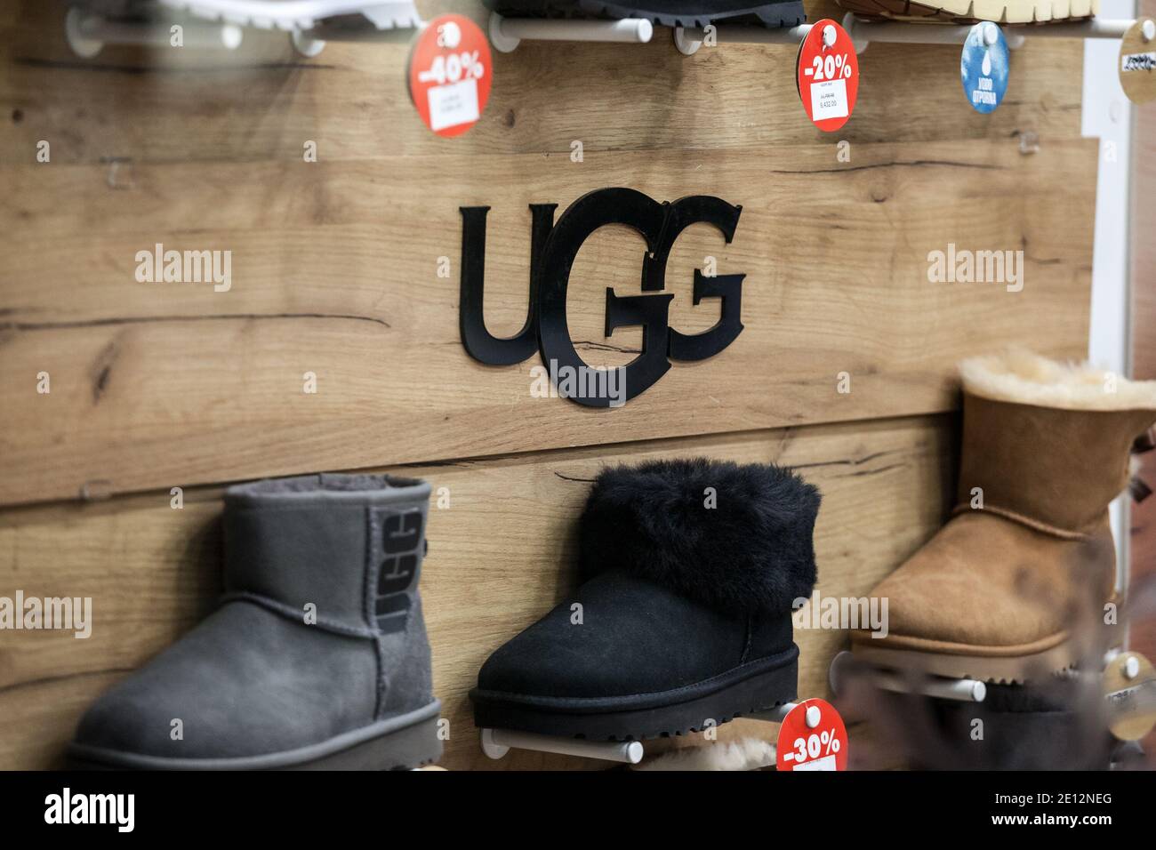 BELGRADO, SERBIA - 8 DICEMBRE 2020: Logo Ugg davanti ad alcuni dei loro  stivali per la vendita in un negozio. Ugg è un marchio americano di  calzature noto per la sua lei