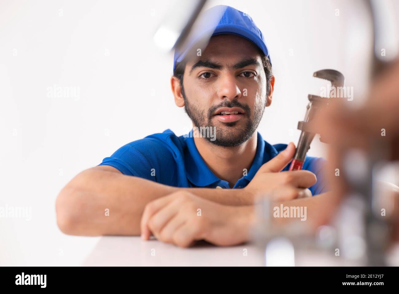 RITRATTO DI UN GIOVANE IDRAULICO CHE TIENE GLI ATTREZZI DURANTE IL LAVORO Foto Stock