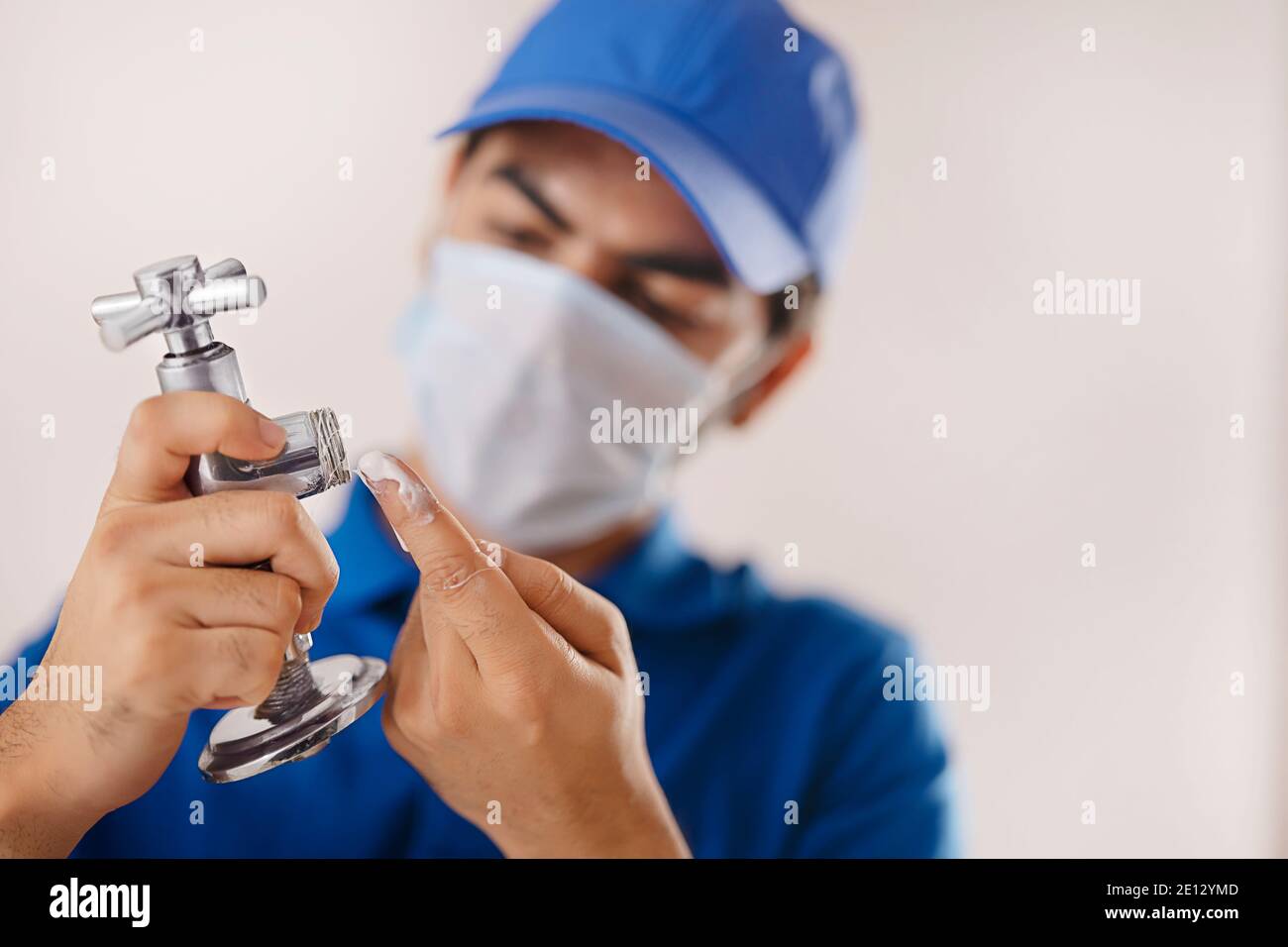 UN TUBO ROTTO CHE VIENE ISPEZIONATO E FISSATO DA UN IDRAULICO INDOSSARE LA MASCHERA FACCIALE Foto Stock