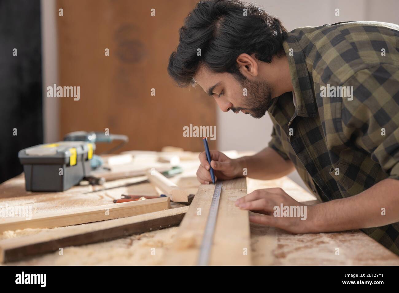 UN FALEGNAME CHE CONTRASSEGNA CON ATTENZIONE LE MISURE PRIMA DI TAGLIARE IL LEGNO Foto Stock