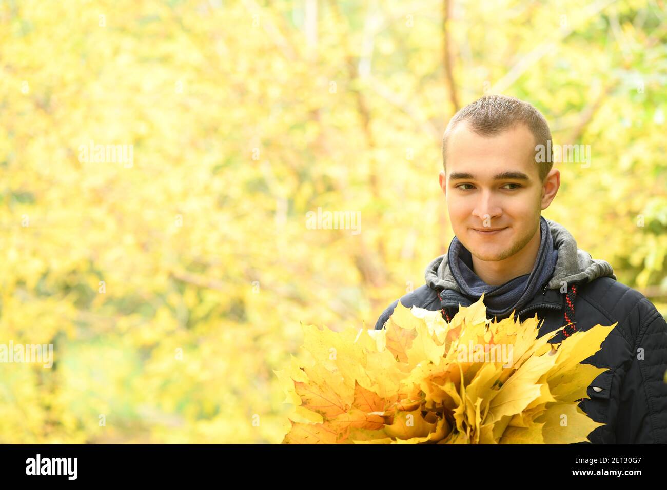 Un uomo tiene in mano un bouquet di foglie d'autunno. Caldo giorno d'autunno, foglie d'autunno gialle. Concetto autunnale. Foto ad alta risoluzione. Foto Stock