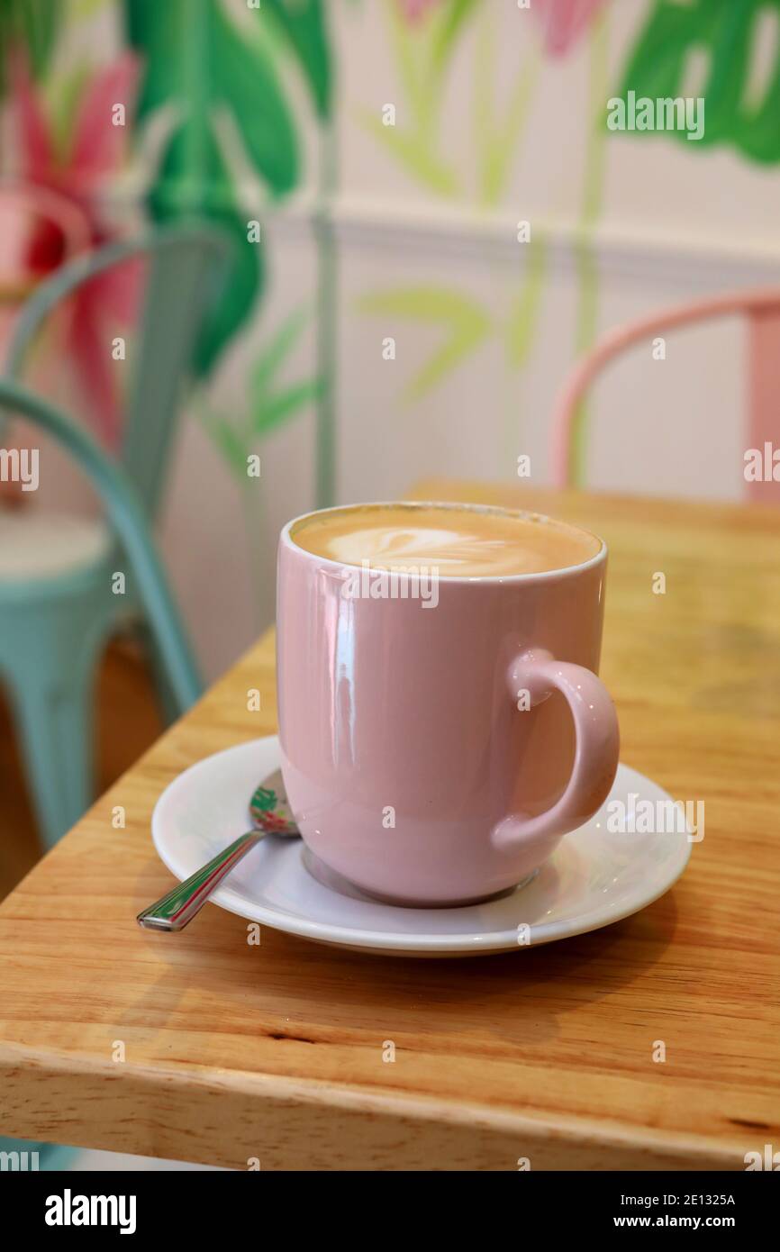 Donna che tiene un caffè gustoso in una tazza rosa presso un caffè a Chichester, West Sussex, Regno Unito. Foto Stock