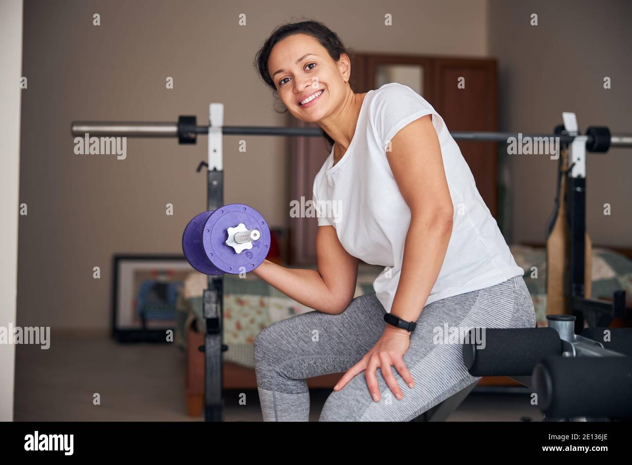 Signora allegra atletica che esegue un esercizio di sollevamento del peso Foto Stock