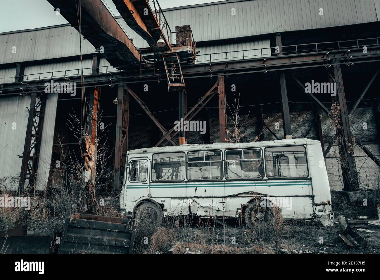 Vecchio autobus rotto arrugginito abbandonato in oscuro paesaggio industriale post apocalittico. Foto Stock