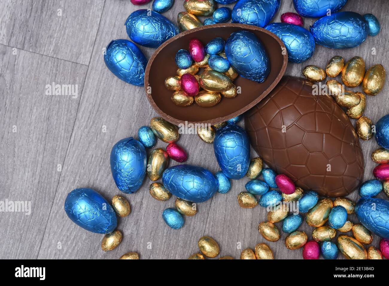 Mucchio o gruppo di colori diversi e di diverse dimensioni di uova di pasqua colorate in foglio di cioccolato in rosa, blu, oro e verde. Metà uova grandi. Foto Stock
