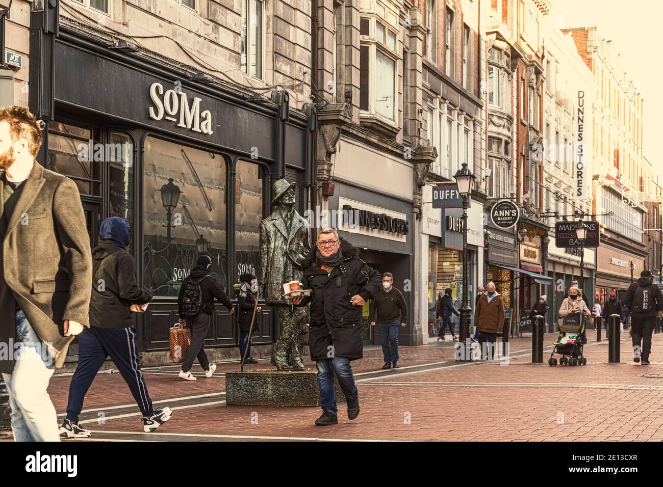 La gente passa accanto alla statua di James Joyce a nord di Earl's Street a Dublino, Irlanda. Foto Stock