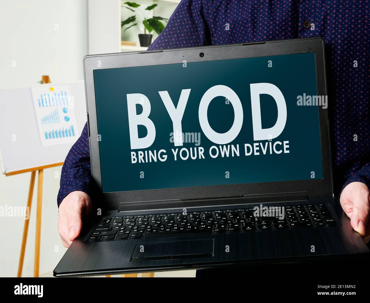 BYOD porta il tuo dispositivo. Un uomo tiene un computer portatile nelle sue mani. Foto Stock