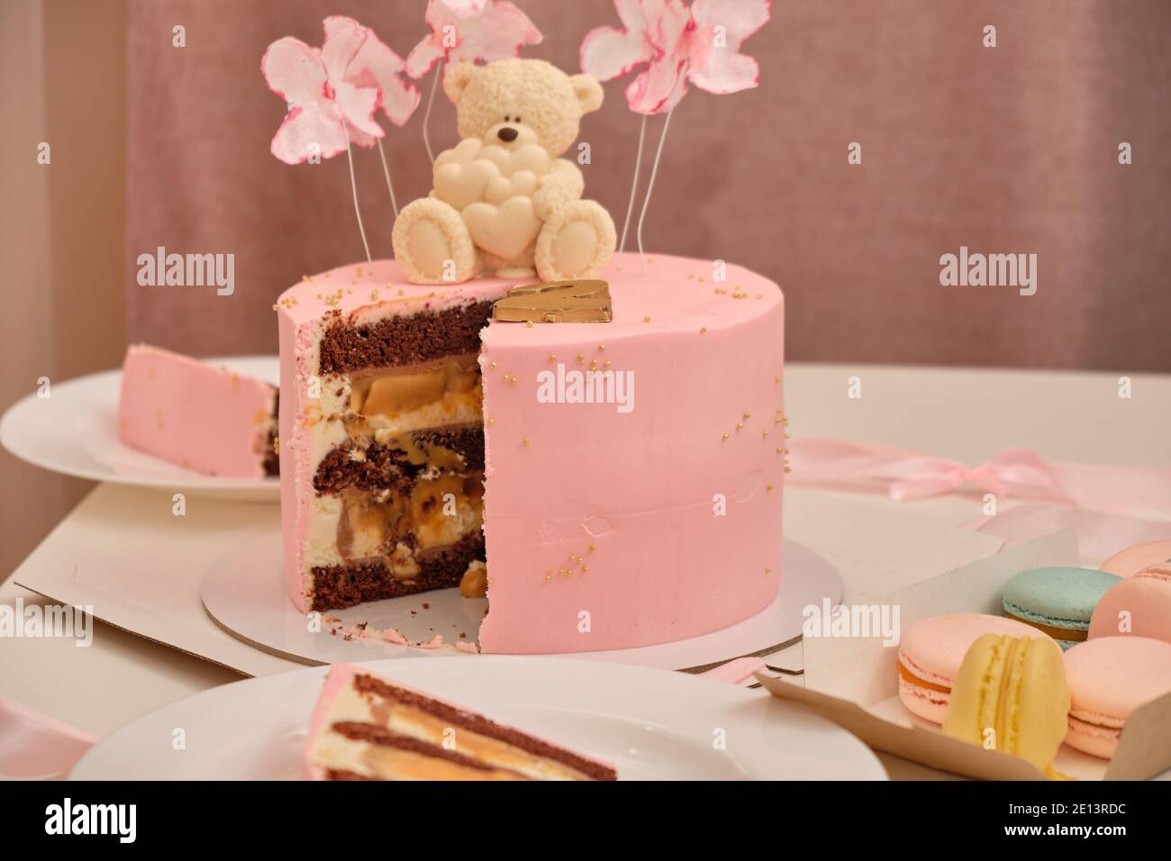 Torta di compleanno rosa rotonda per un bambino di 2 anni. Orsetto di cioccolato bianco con cuori sulla torta Foto Stock