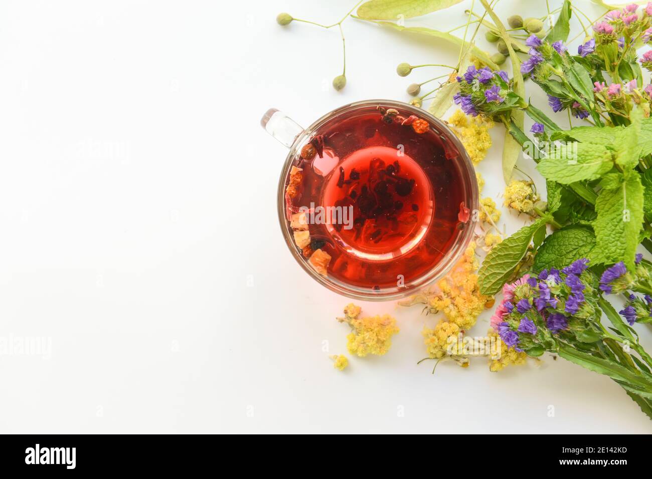 Fiori secchi, erbe e tazza di tè floreale su sfondo bianco Foto Stock