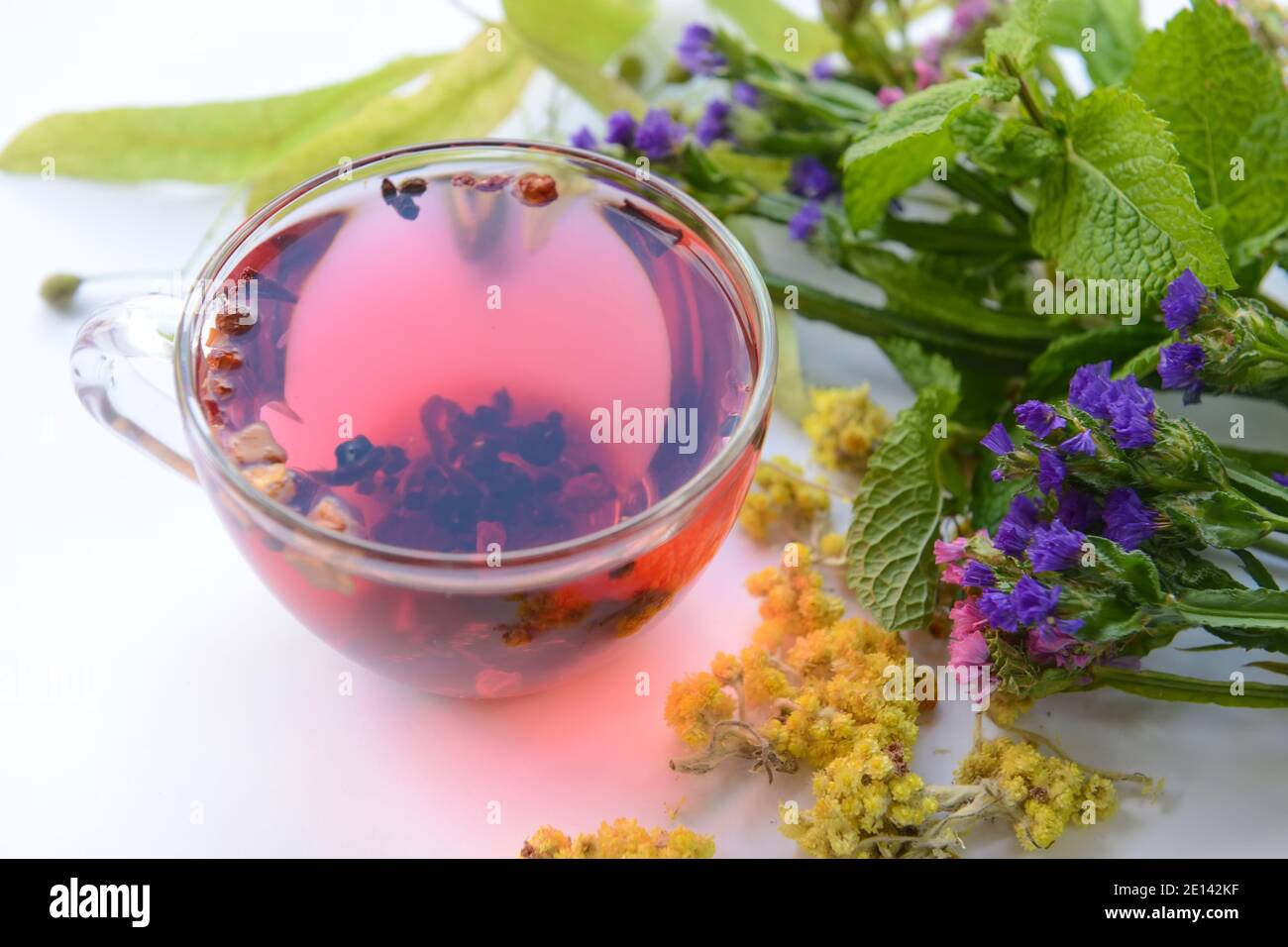 Fiori secchi, erbe e tazza di tè floreale su sfondo bianco Foto Stock