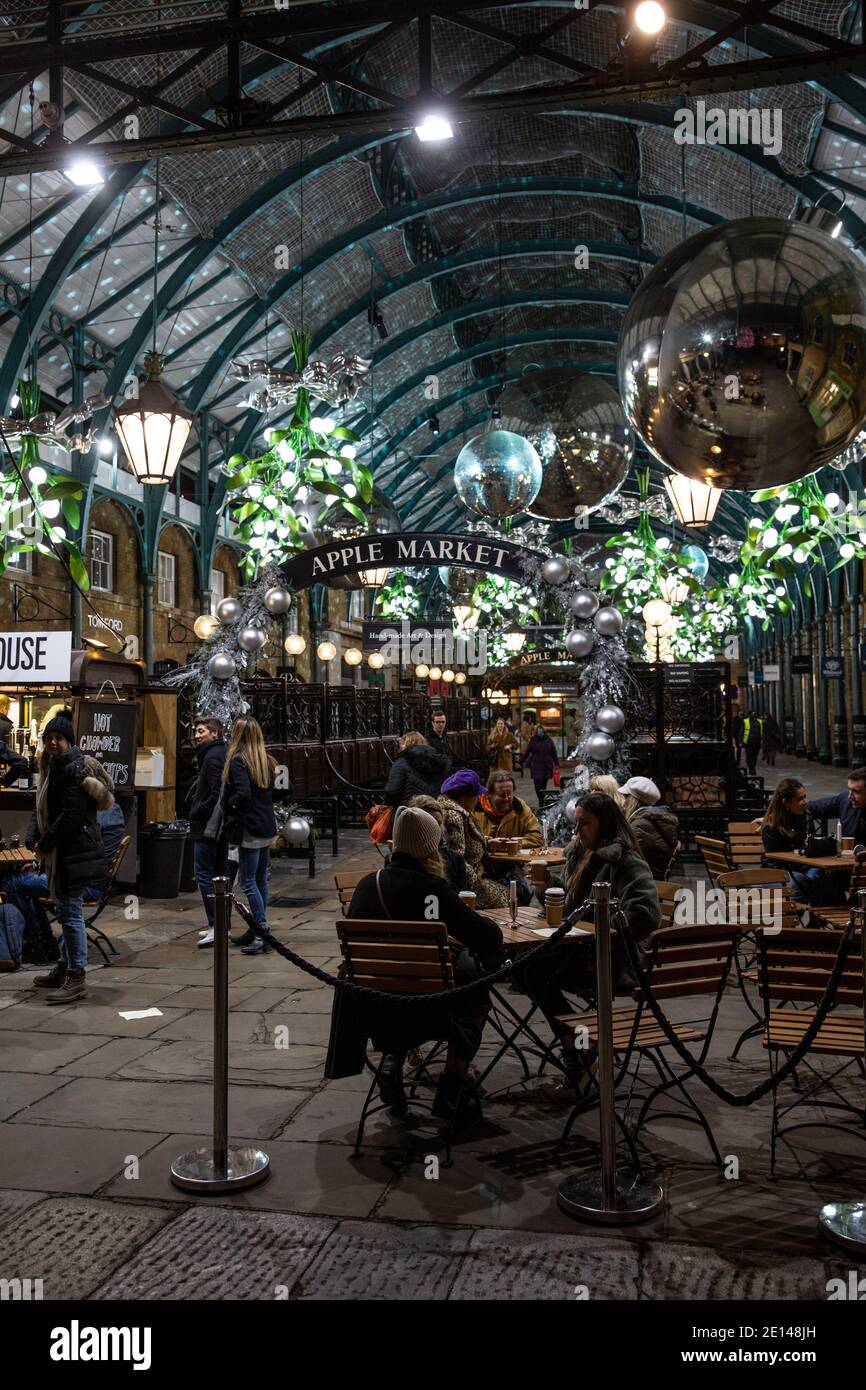 Gli acquirenti di Natale si siedono e portano via un caffè socialmente distanziato nella Covent Garden Piazza durante le misure di Lockdown di Tier2 Coronavirus, Londra UK Foto Stock