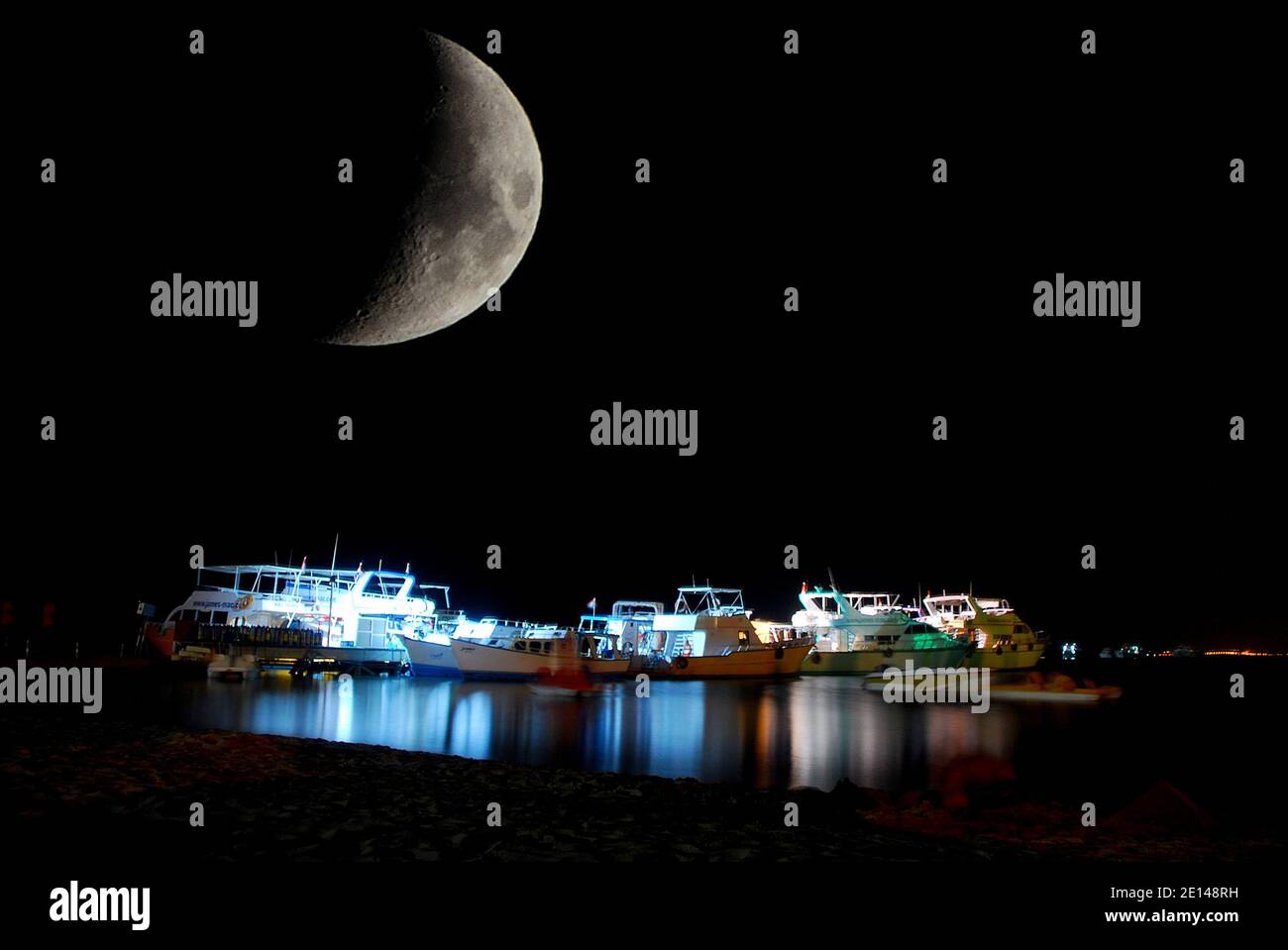 barche illuminate sulla spiaggia di notte Foto Stock