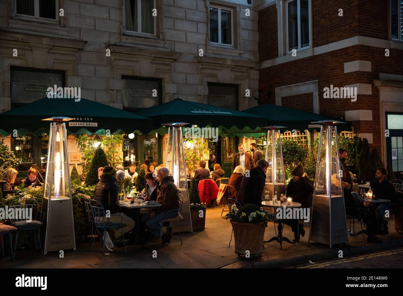 La gente siede fuori del ristorante Ivy socialmente distanziato durante le restrizioni pandemiche del coronavirus sulla corsa fino a Natale 2020, Londra, Inghilterra. Foto Stock