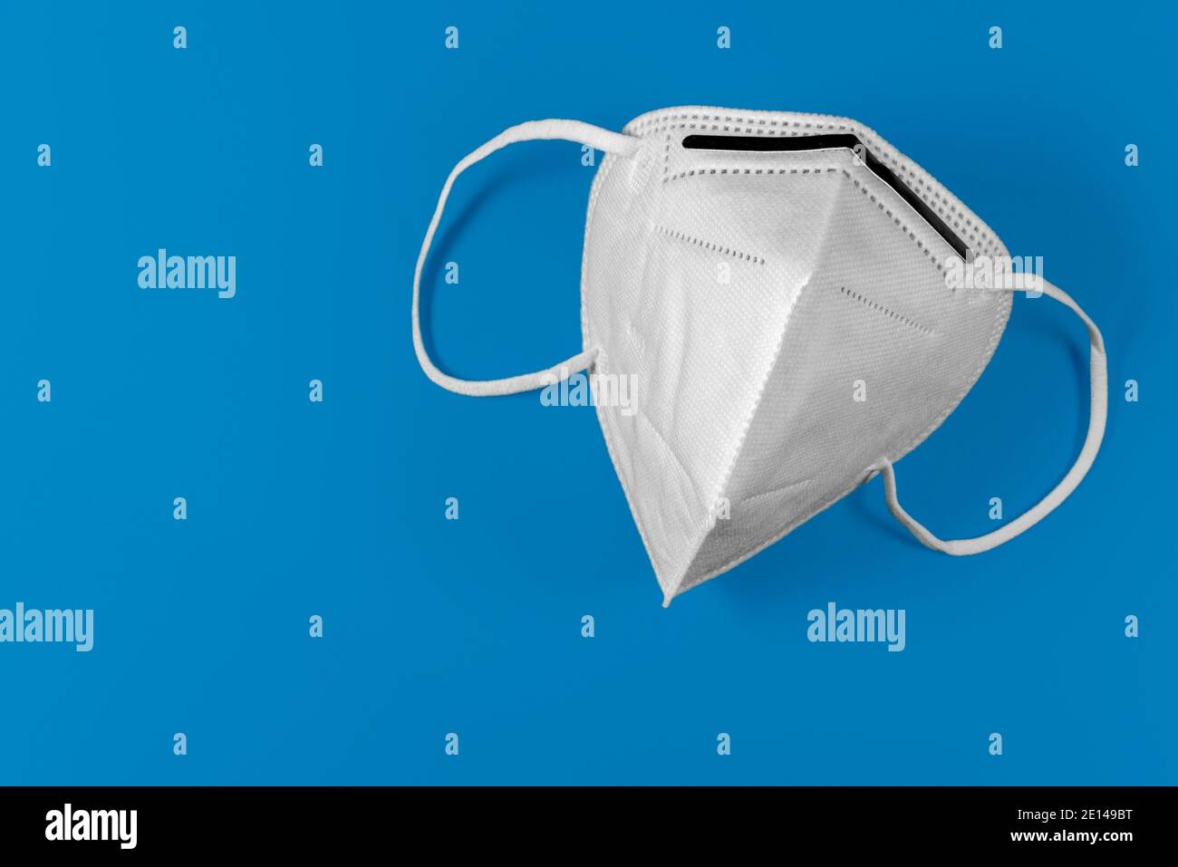 Maschera bianca KN95 o FFP2 su sfondo blu. Maschera medica per la protezione Covid-19 per prevenire la pandemia del coronavirus Foto Stock