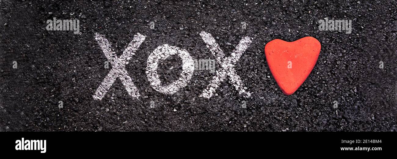 XOXO scritto a terra con una pietra a forma di cuore, giorno di San Valentino banner web Foto Stock