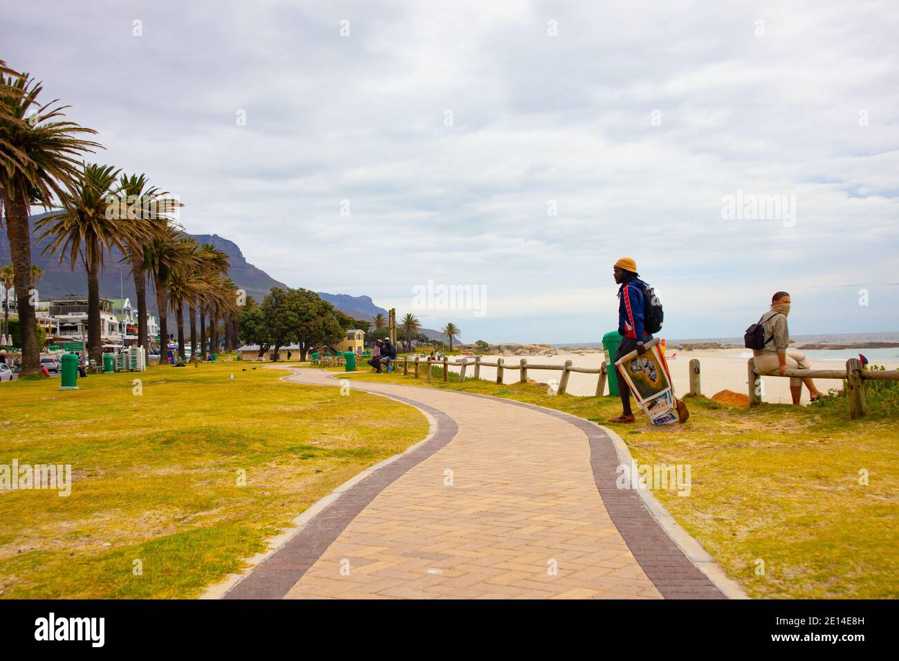 Camps Bay- Città del Capo, Sud Africa - 23/11/2020 Camps Bay Boardwalk in un caldo, pomeriggio coperto. Uomo che cammina con la sua opera d'arte in mano. Foto Stock Camps Bay- Città del Capo, Sud Africa - 23/11/2020 Camps Bay Boardwalk in un caldo, pomeriggio coperto. Uomo che cammina con la sua opera d'arte in mano. Foto Stock