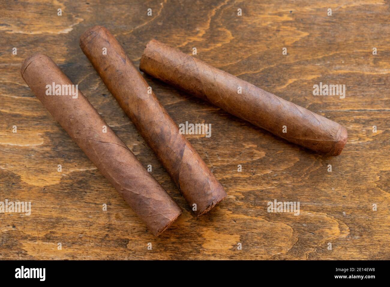 Sigari su un tavolo di legno, vista guardaroba. Tre sigari cubani fatti a mano di qualità, fumo di tabacco stile di vita di lusso. Foto Stock
