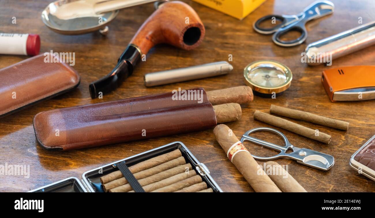 Accessori per fumatori. Sigari, pipe, sigaretti e sigarette, taglierine,  accendini, casse su sfondo di un tavolo di legno. Sigari cubani di qualità,  l Foto stock - Alamy