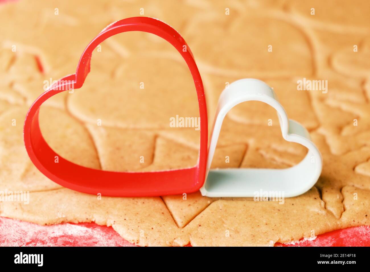 Pasta per preparare biscotti a forma di cuore il giorno di San Valentino. Pasticceria fatta in casa. Stampi da forno in plastica rossa e verde. Foto Stock