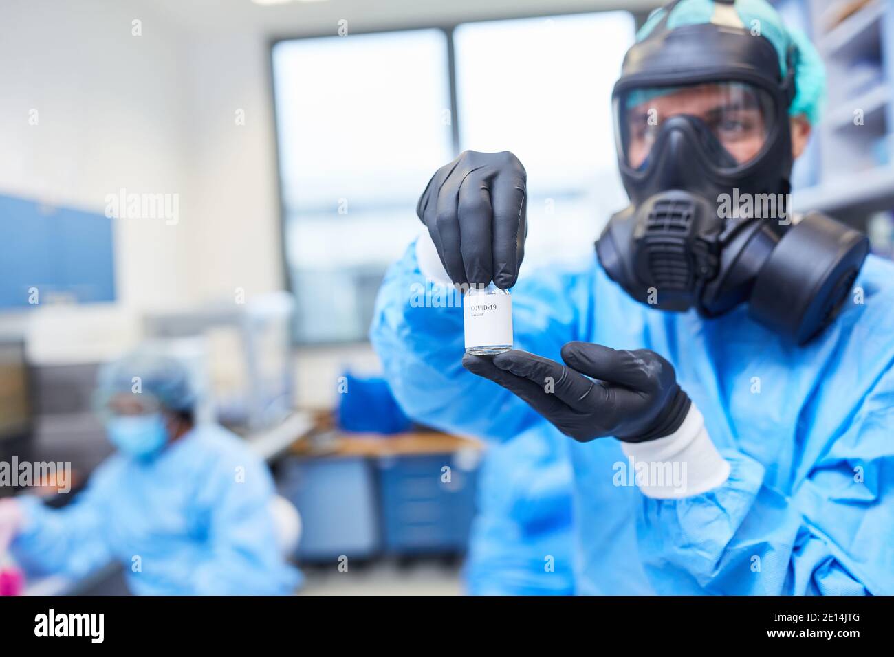 Ricercatori con indumenti protettivi in laboratorio con una fiala Di un vaccino Covid-19 nella pandemia del coronavirus Foto Stock