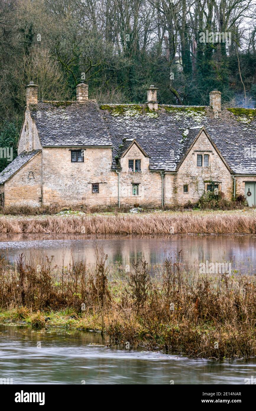 Riflessione di Arlington Row visto in acque alluvionali dal fiume Coln su rack Isle nel dicembre 2020 nel villaggio di Cotswold di Bibury, Gloucestershire UK Foto Stock