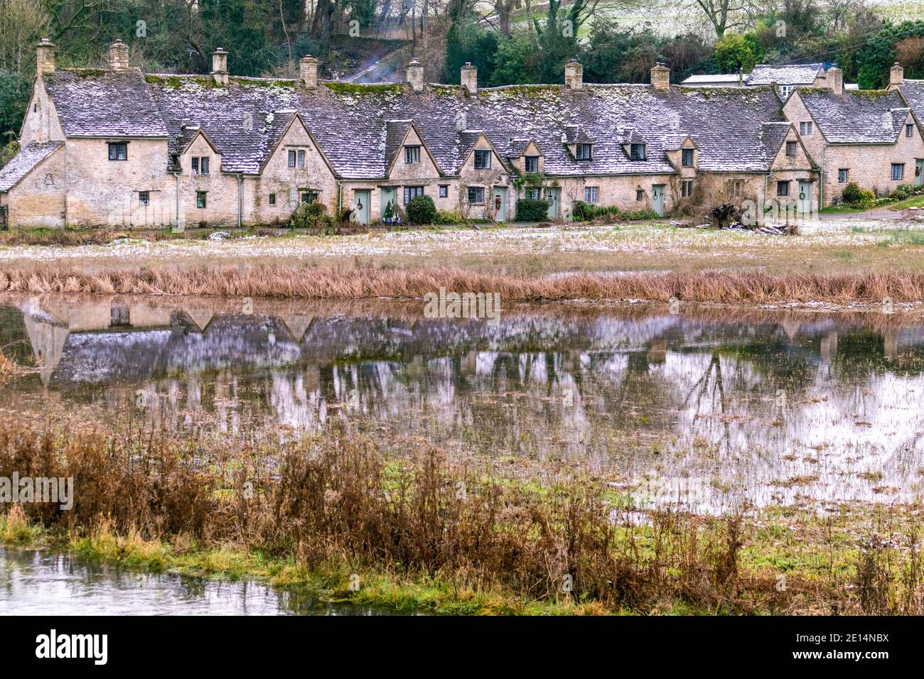Riflessione di Arlington Row visto in acque alluvionali dal fiume Coln su rack Isle nel dicembre 2020 nel villaggio di Cotswold di Bibury, Gloucestershire UK Foto Stock