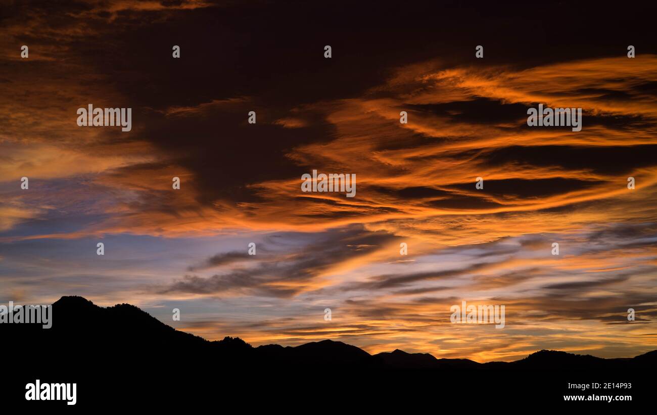 Fantastiche e colorate nuvole al tramonto sulla silhouette delle colline scure Foto Stock