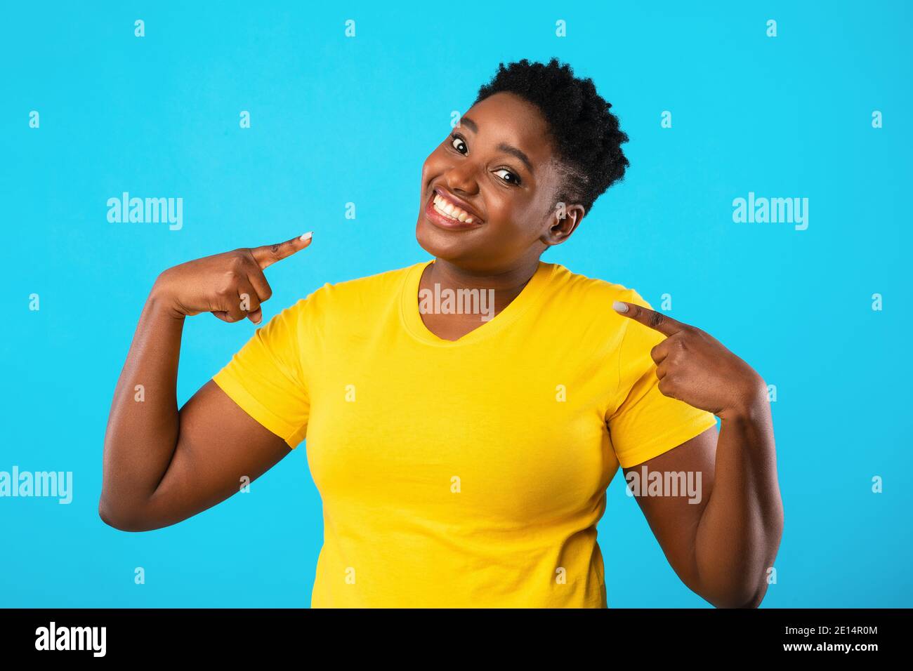 Donna nera Confident Plus-Size che punta le dita verso se stessa, sfondo blu Foto Stock