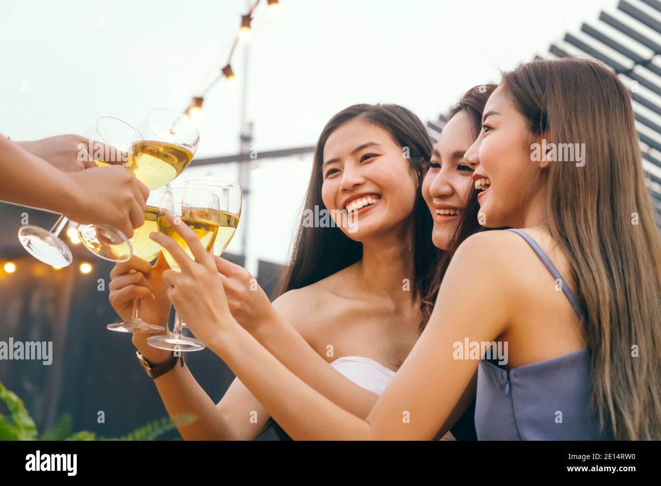 happy asian teenager cheering e brindisi con bianco bicchiere di vino frizzante per celebrare alla festa di cena in estate. fuoco selettivo. celebrat Foto Stock
