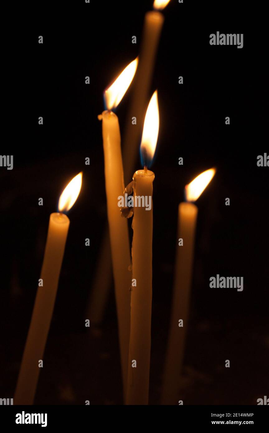 Cinque candele sottili su sfondo scuro. Cera gocciolante. Foto Stock