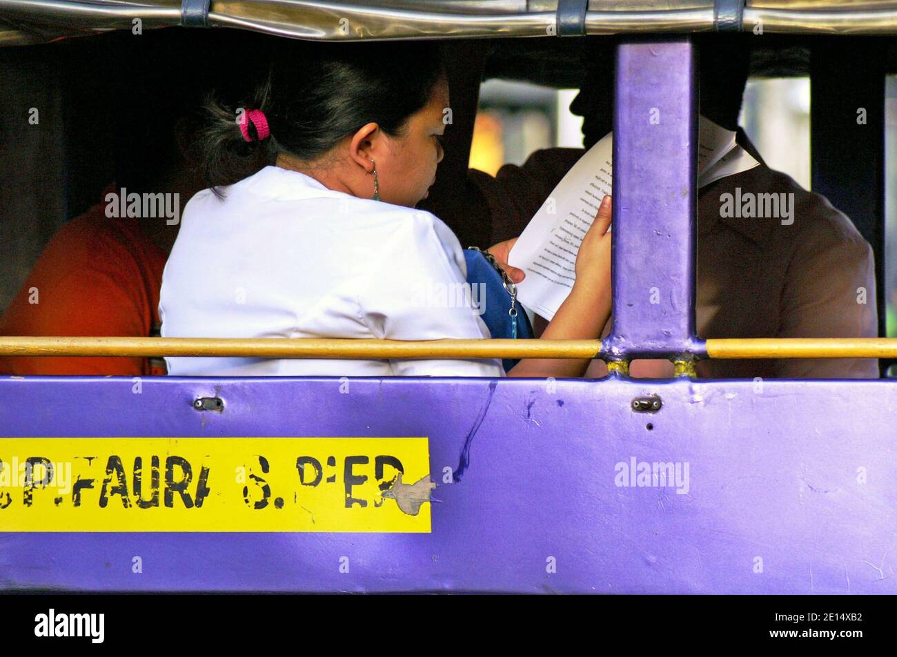 I filippini prendono un Jeepney a Manila, Filippine. Il mezzo di trasporto iconico include jeepney pubblici e privati che si impanano su diversi percorsi scritti sul lato del veicolo. Unica per le Filippine, questa modalità di trasporto ha trovato il suo modello nelle jeep militari in eccesso lasciate dagli Stati Uniti dopo la seconda guerra mondiale Negli ultimi anni i veicoli sono diventati più regolamentati, tra cui un programma di eliminazione graduale dei jeepneys di oltre 15 anni. Foto Stock