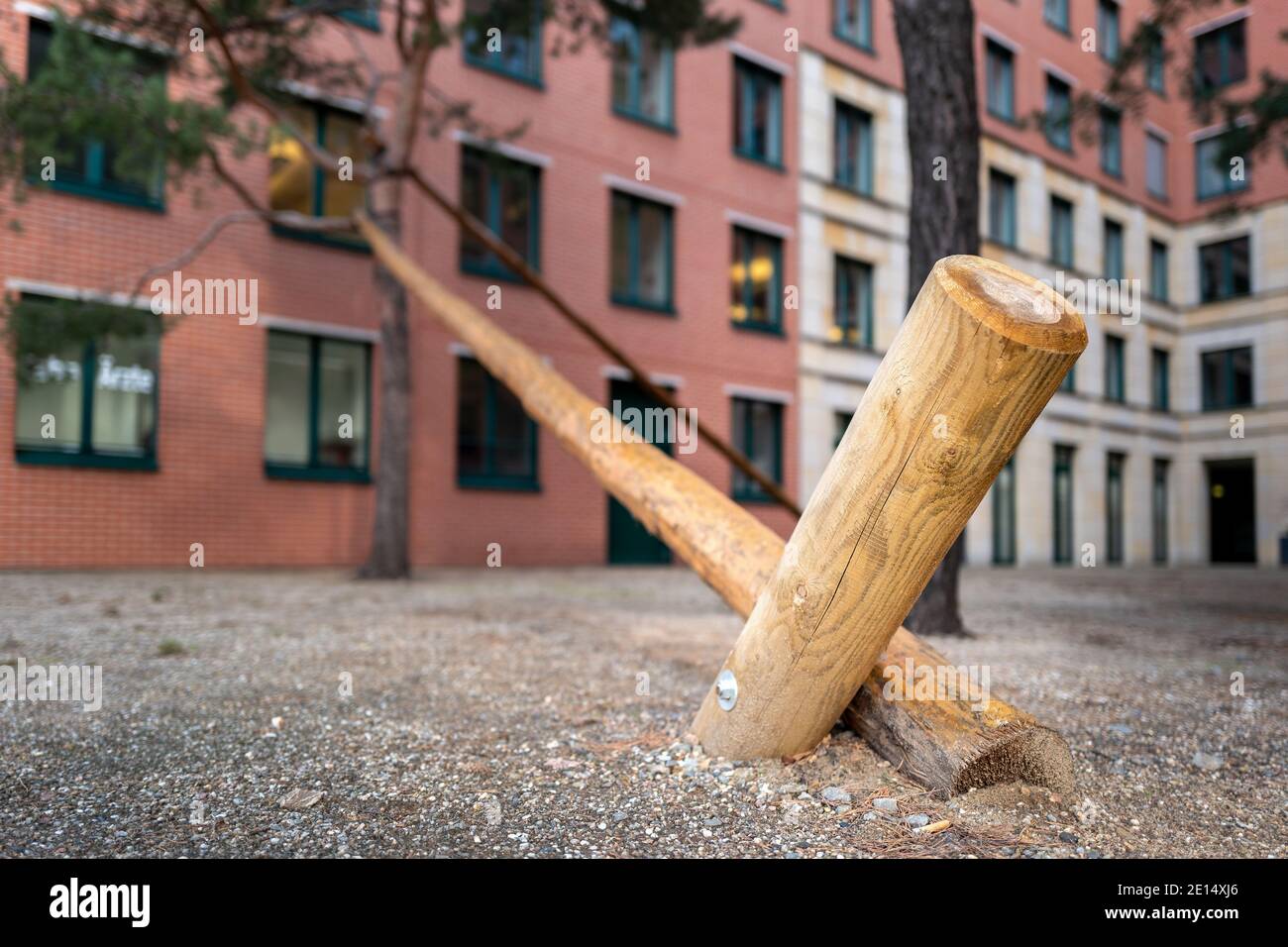 La posta di legno sostiene UN albero nella città Foto Stock