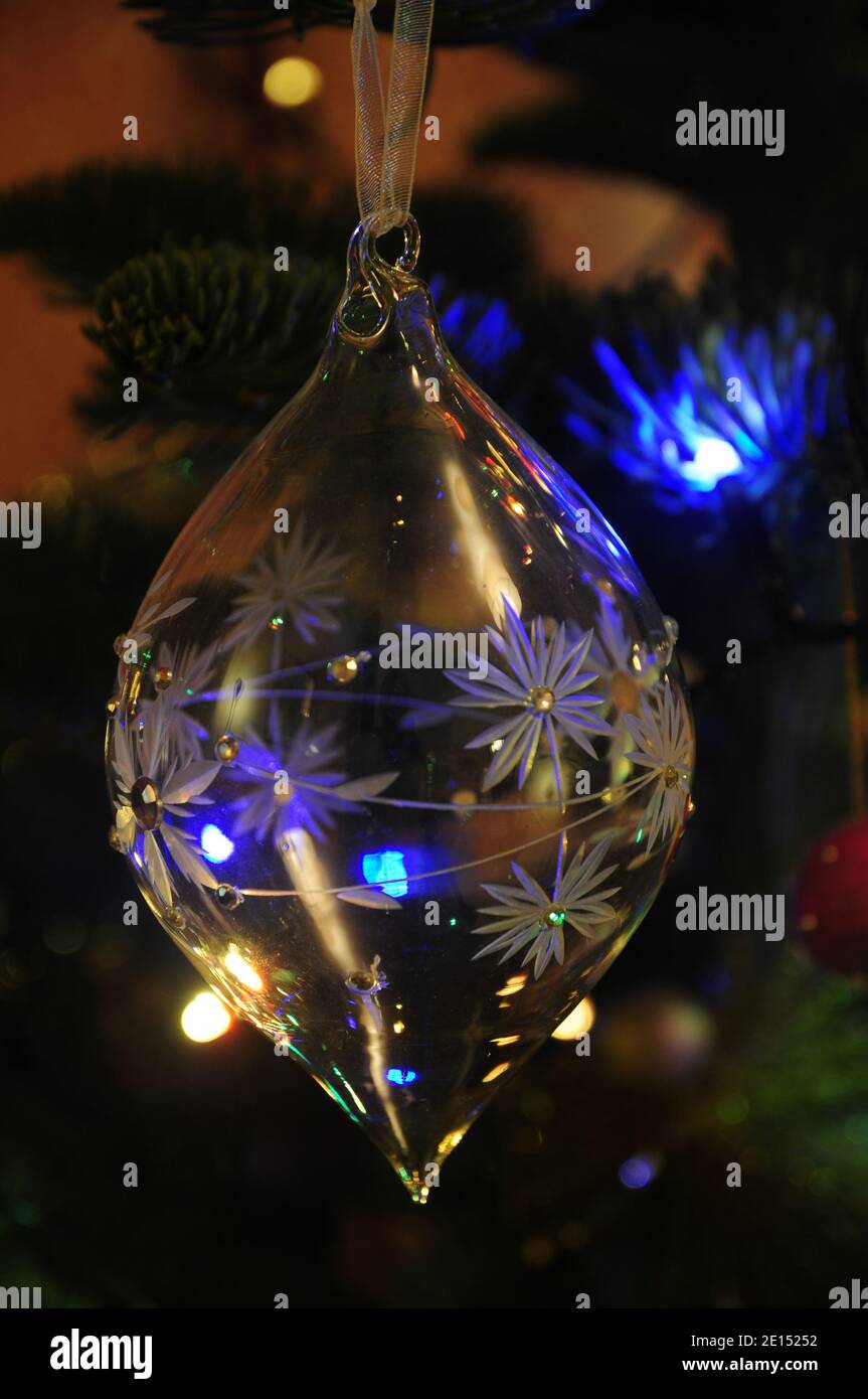 Tagliare vetro albero di Natale bauble appeso su un albero di Natale e illuminato da fata luci. Foto Stock